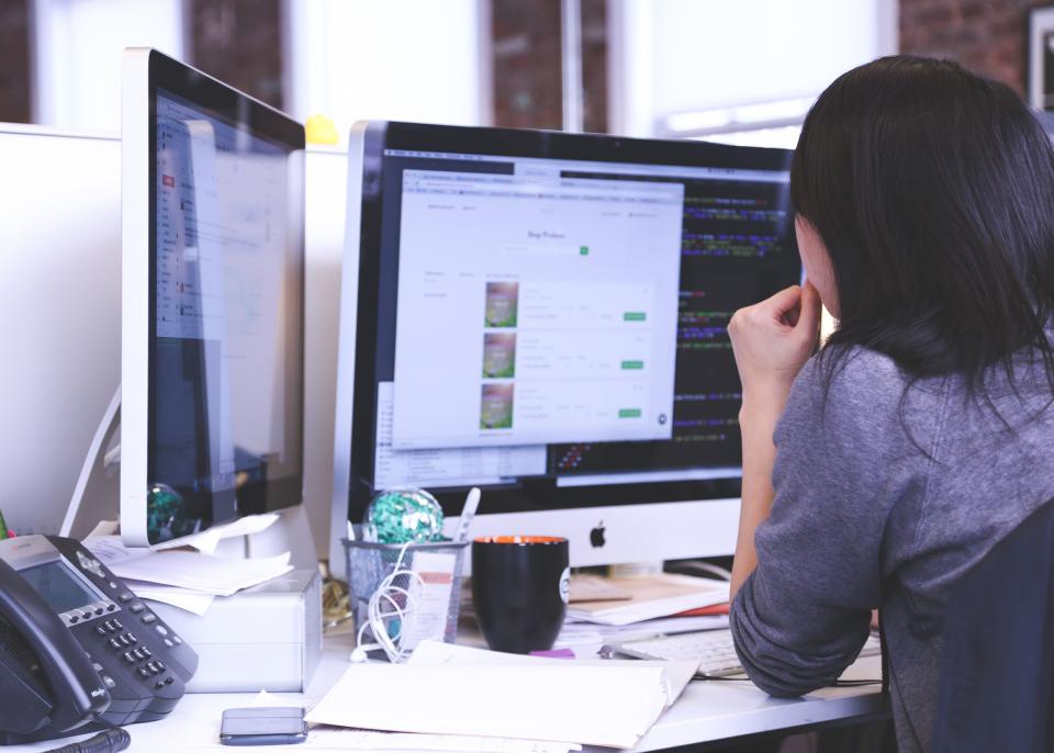 Person reviewing custom software on a computer screen, comparing it to off-the-shelf options