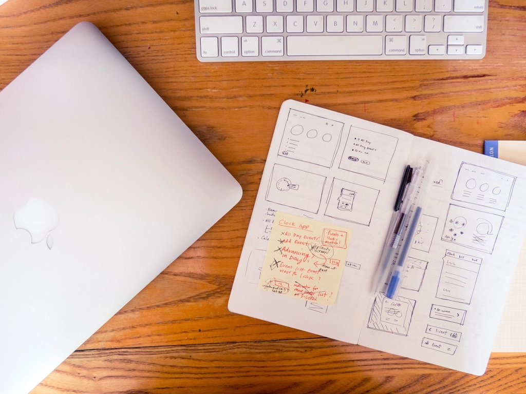 Website wireframe sketches in a notebook next to a laptop